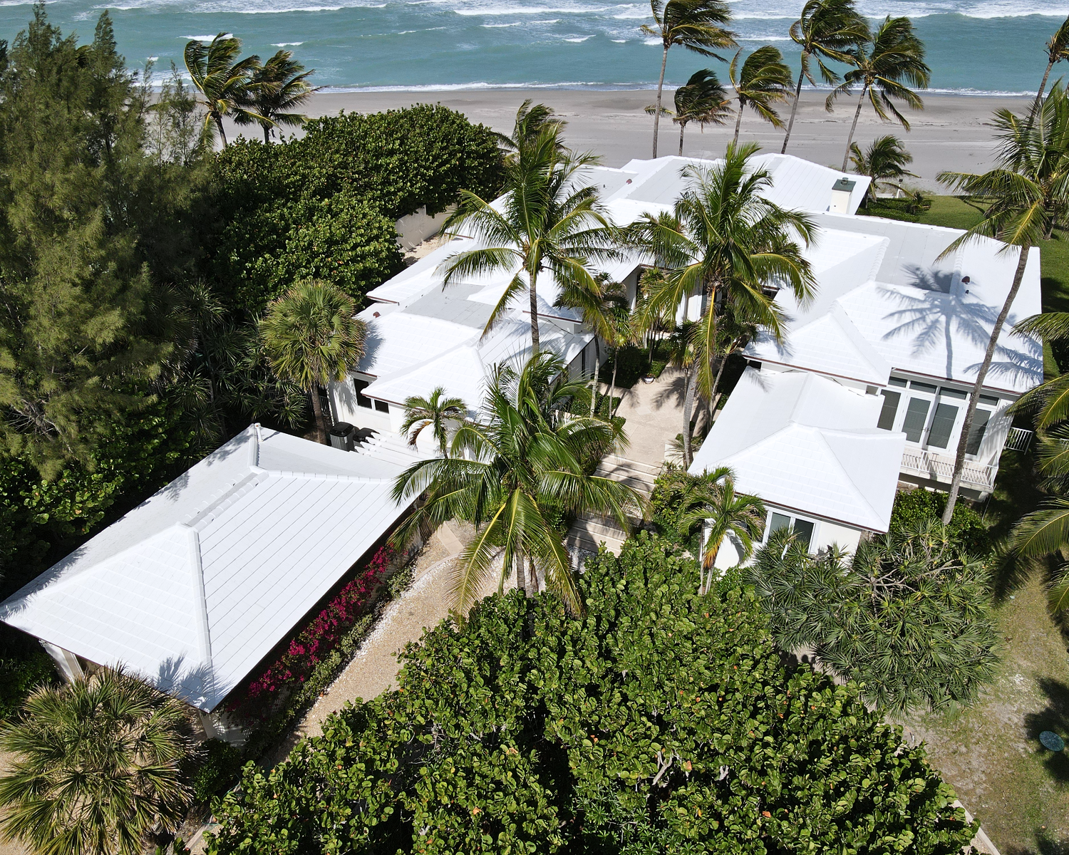An aerial view of a house on a beach with palm trees