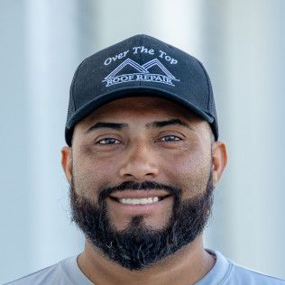 A man with a beard is wearing a hat and smiling.