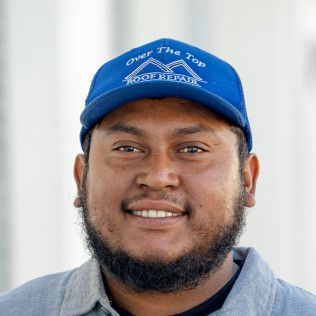 A man with a beard is wearing a blue hat and smiling.