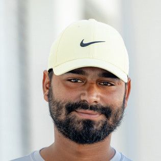 A man with a beard is wearing a white nike hat.