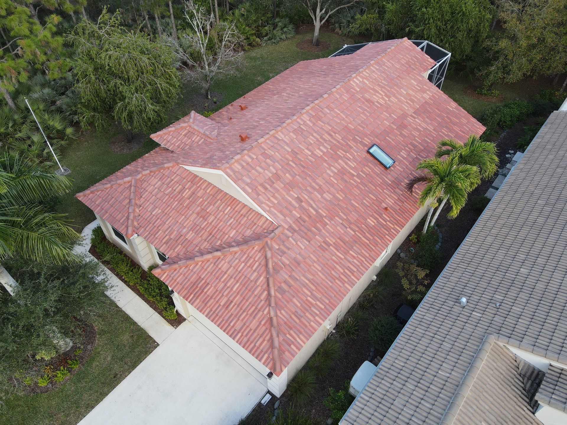 Aerial view of a red-roofed house beside trees and a driveway