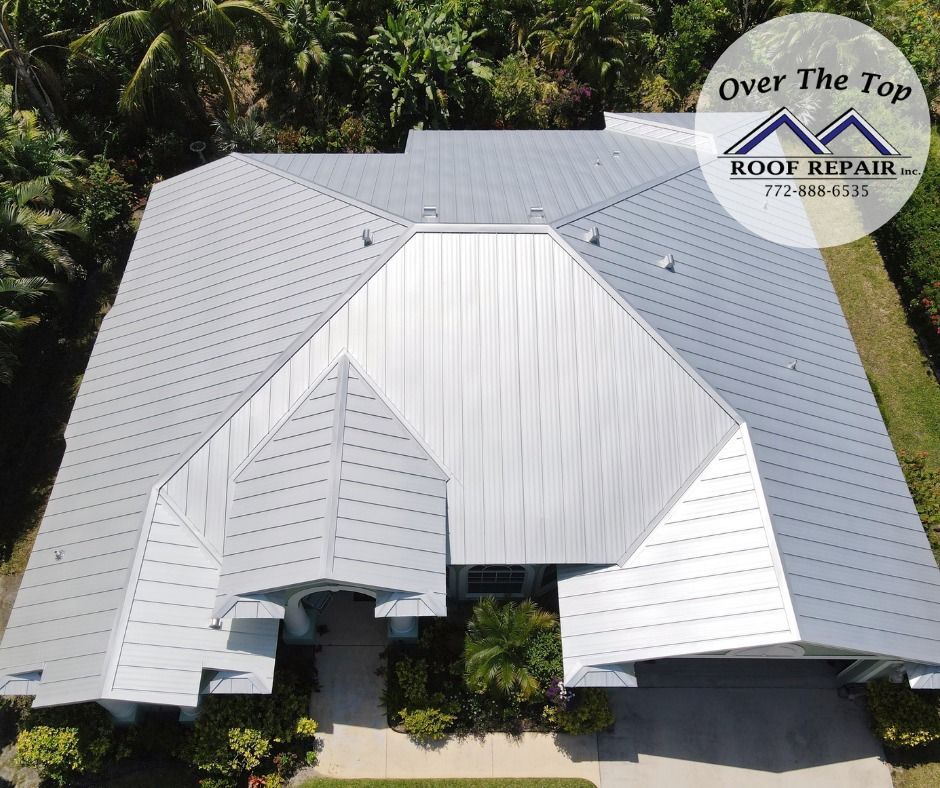 Aerial view of a white metal roof with multiple gables and a roof repair logo in the corner