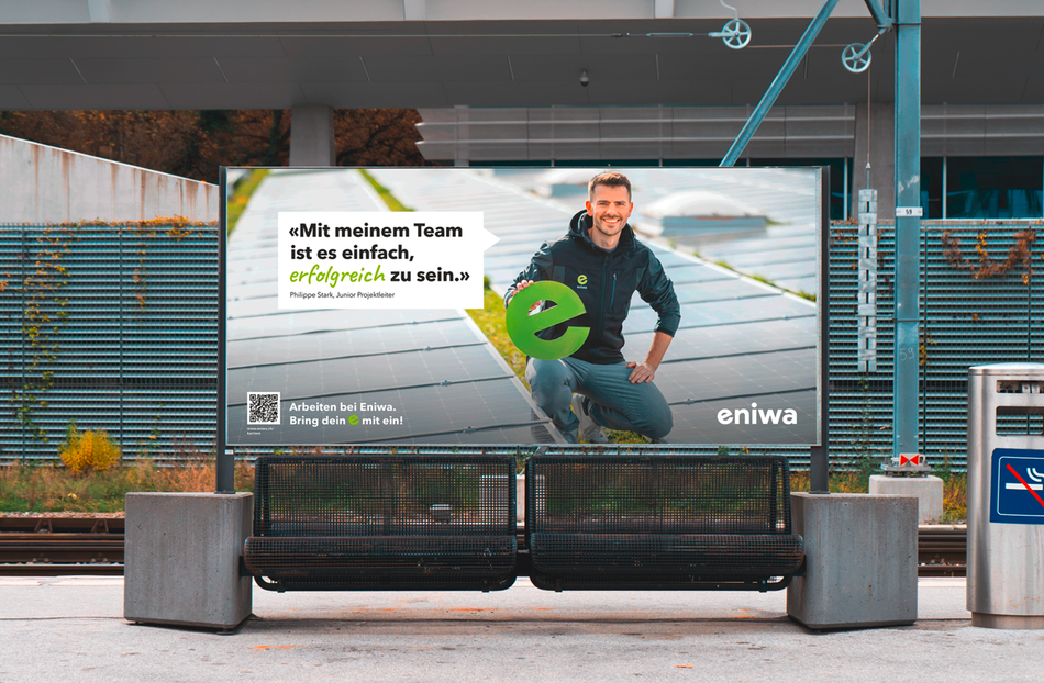Bushaltestellenwerbung mit einem Mann, der ein Fahrrad hält, und einem großen grünen „e“-Logo in einer modernen Wartehalle