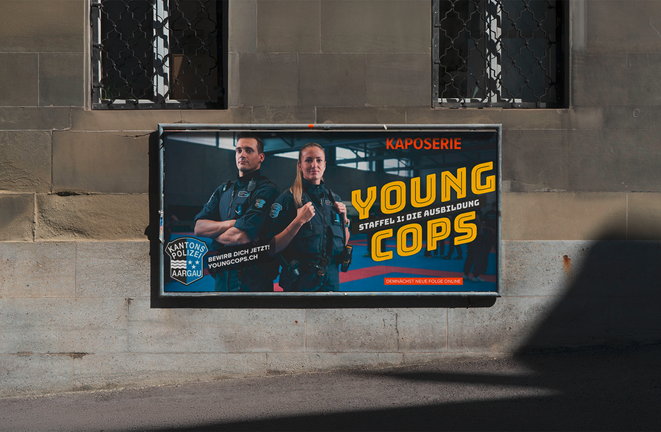 Ein Plakat für „Young Cops“ hängt an einer Wand und zeigt zwei uniformierte Beamte sowie den Titel in fetten gelben Lettern.