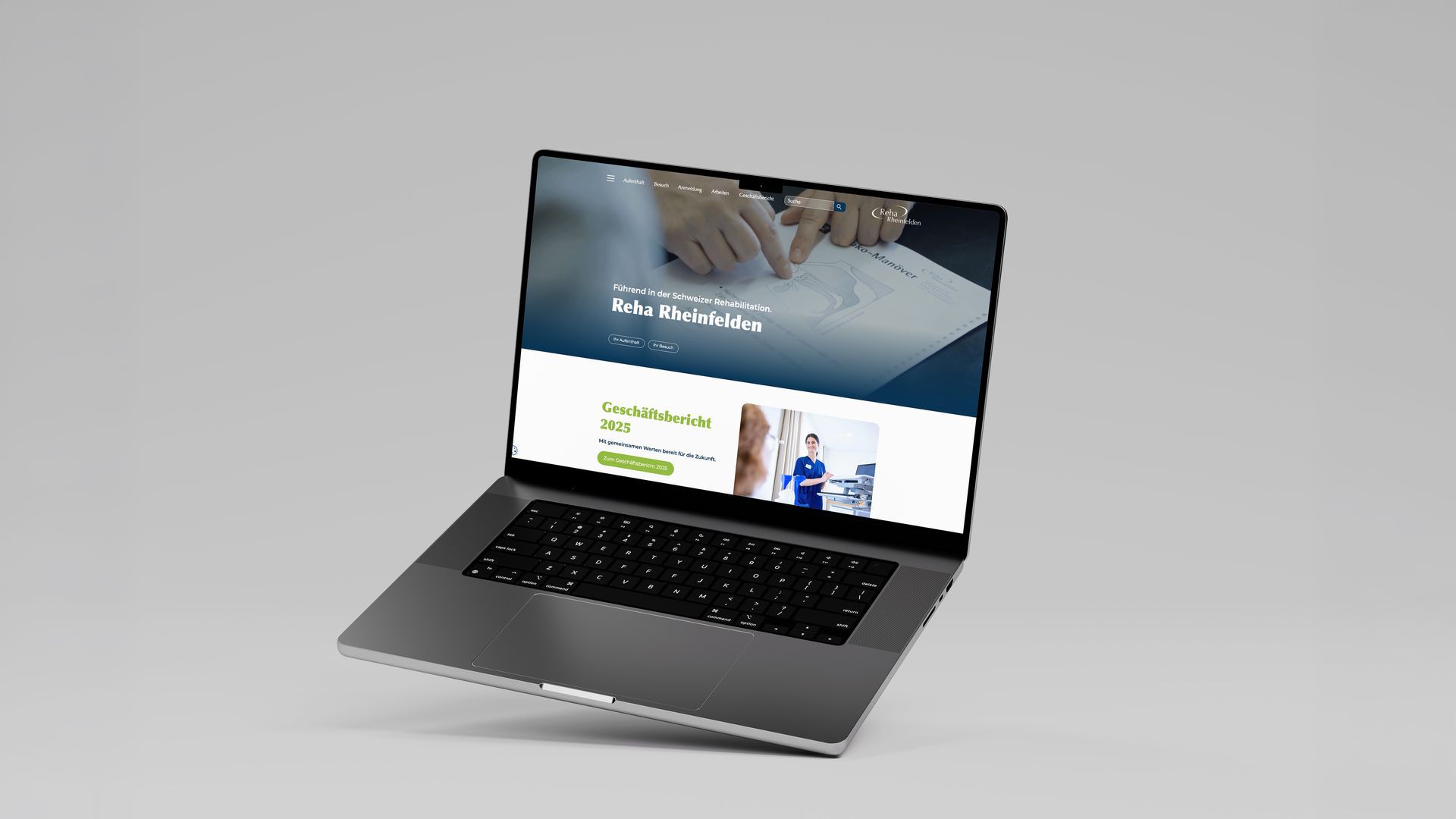 Silberner Laptop mit der Website eines Unternehmens auf grauem Hintergrund