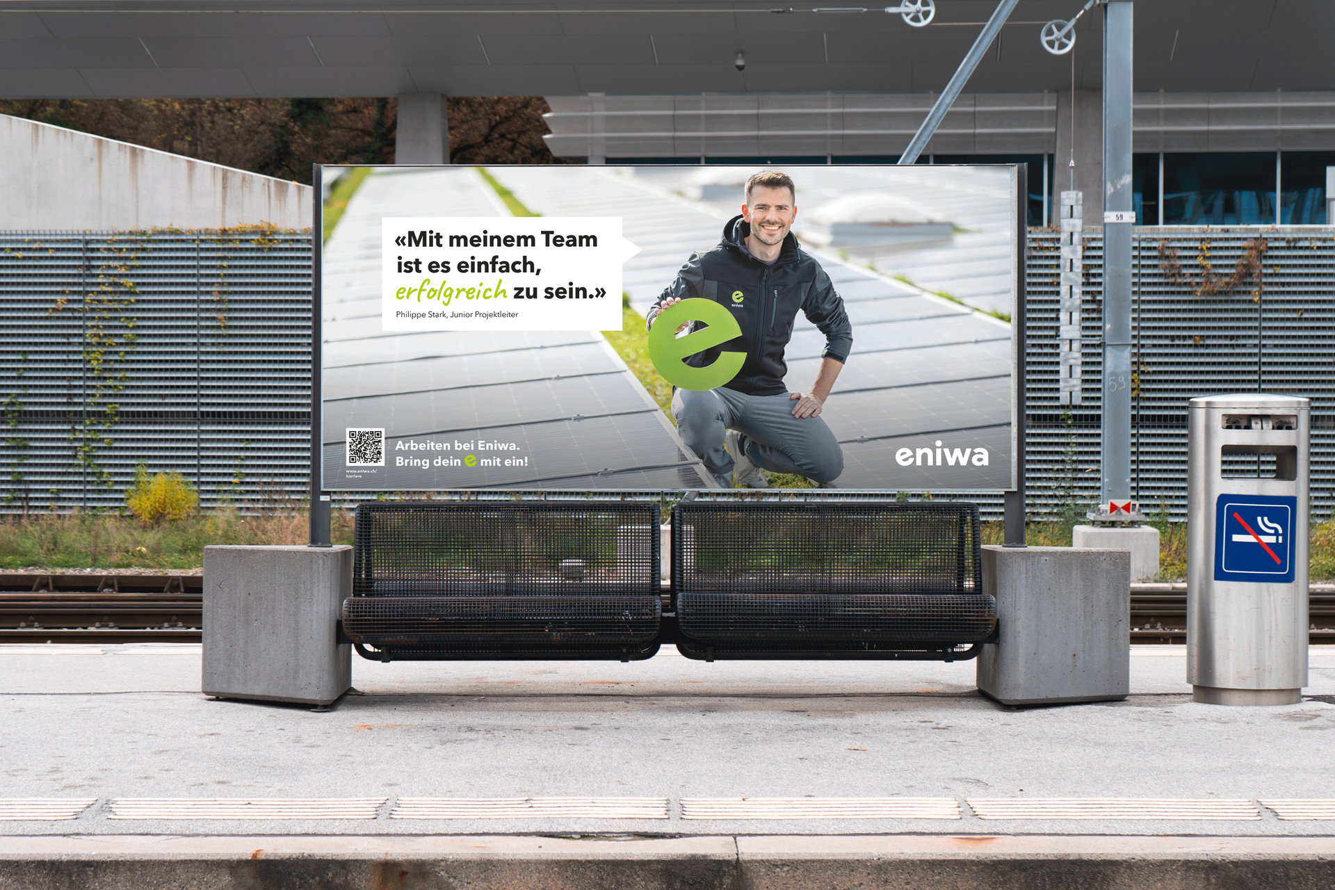 Ein Mann steht neben einer Werbetafel zur Fahrradsicherheit an einer Bushaltestelle in einer Stadtstraße.