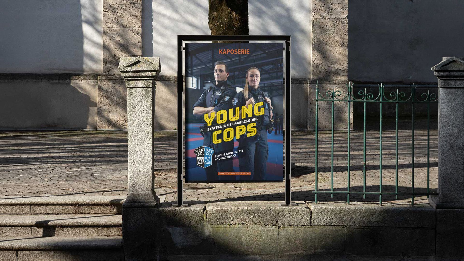 Plakat für „Funky Cops“ an einer Steinmauer neben einem Metallzaun bei Tageslicht