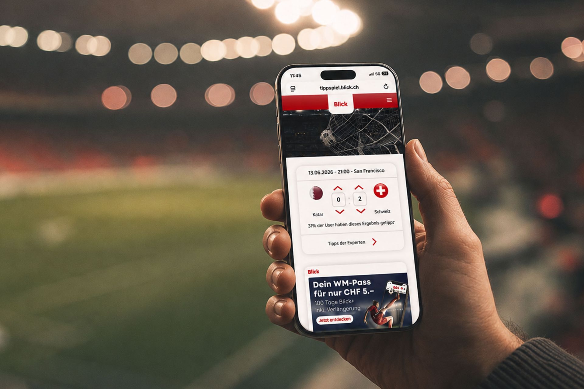 Eine Hand hält nachts in einem Stadion ein Smartphone, auf dem eine Sport-App angezeigt wird.
