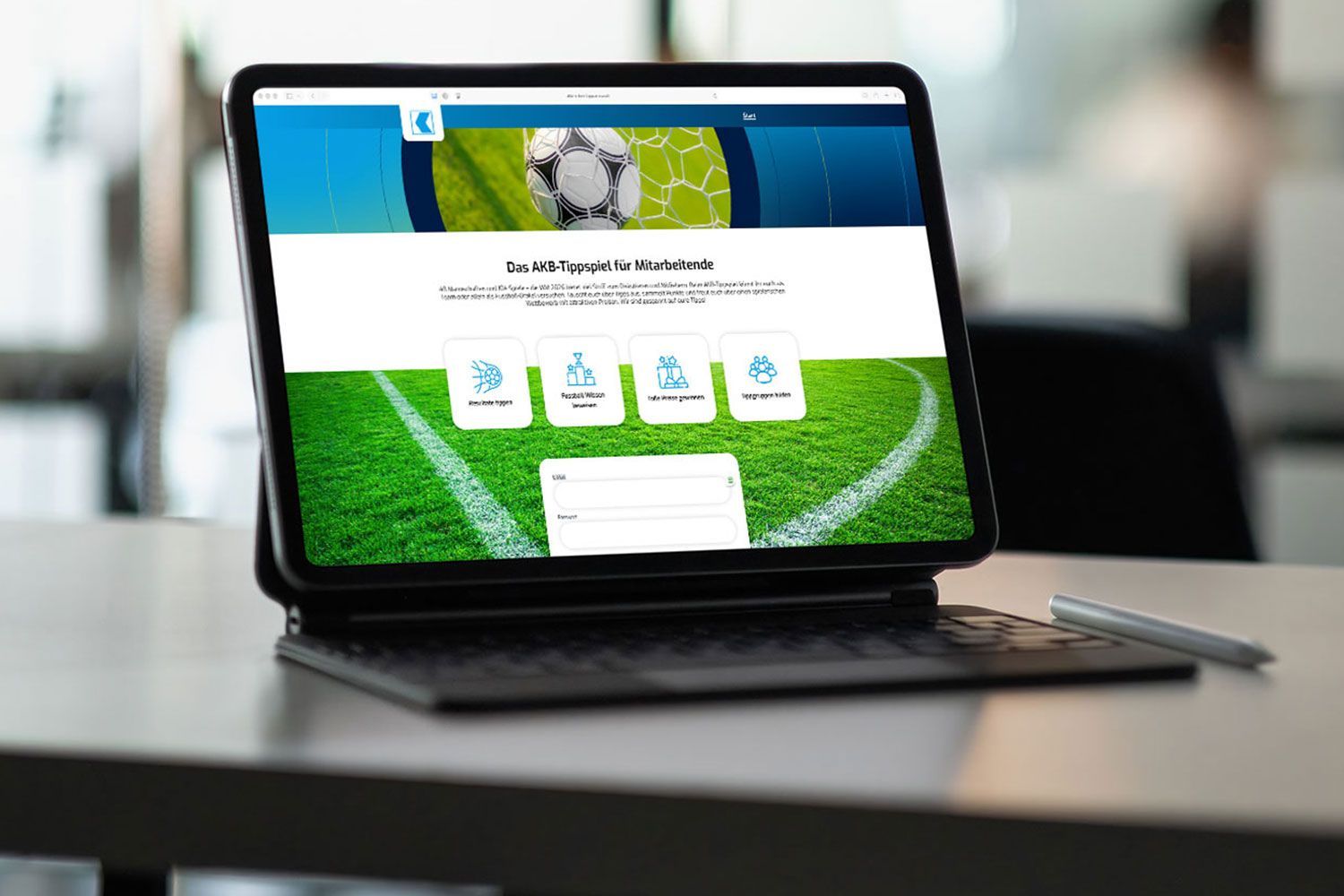 Auf einem Schreibtisch steht ein Laptop, auf dem eine Sportwebsite mit einem Fußballfeld im Hintergrund angezeigt wird.