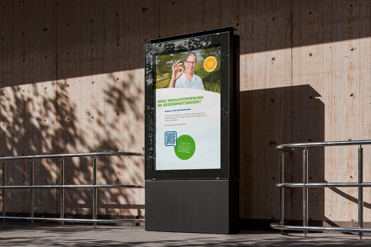 Digitaler Außenkiosk mit Plakatwerbung neben einem Geländer auf einem sonnigen Bürgersteig