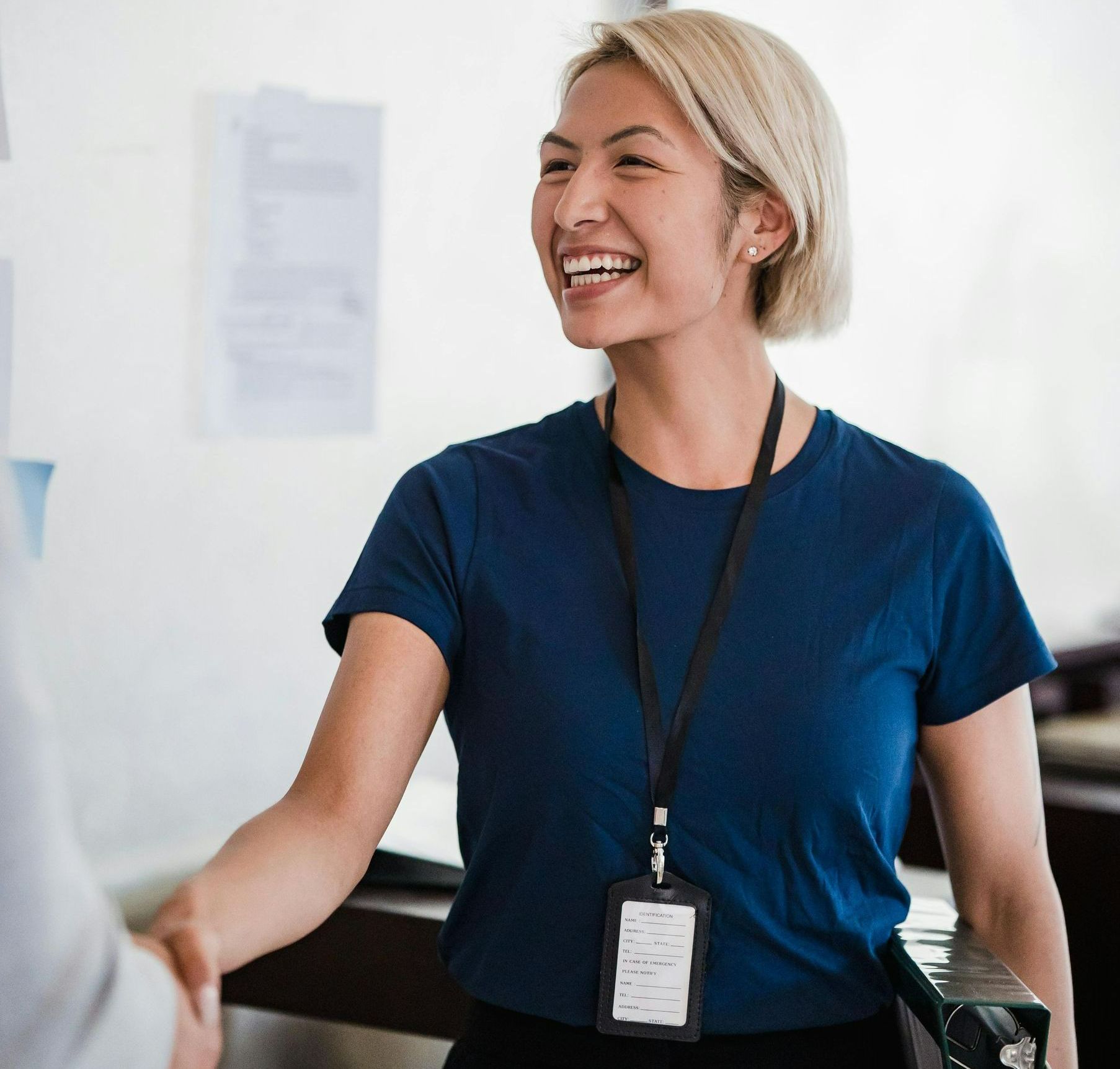A woman in a blue shirt is shaking hands with another woman.