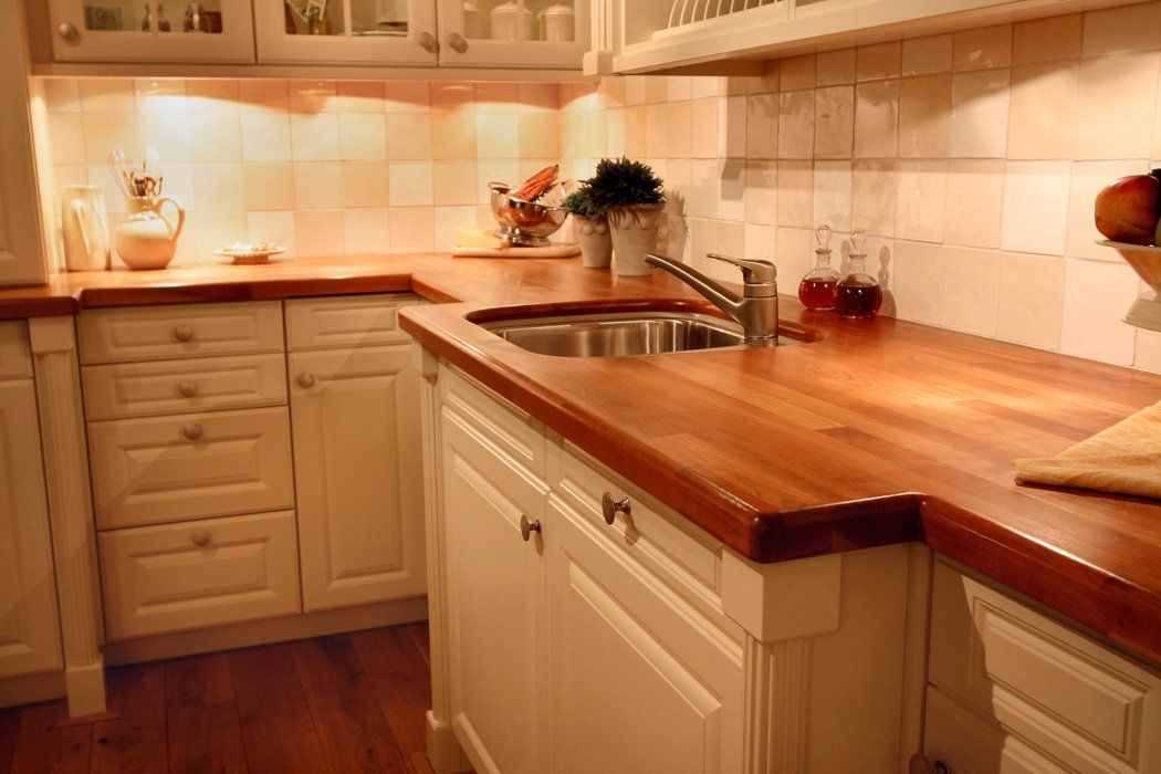 A kitchen with wooden counter tops and white cabinets