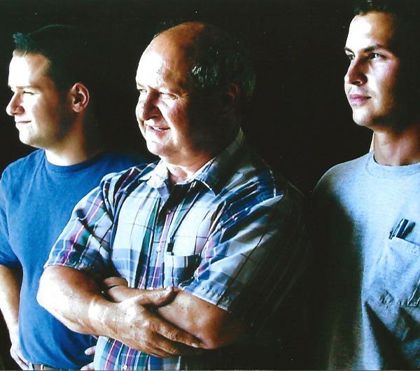 Three men are standing next to each other with their arms crossed