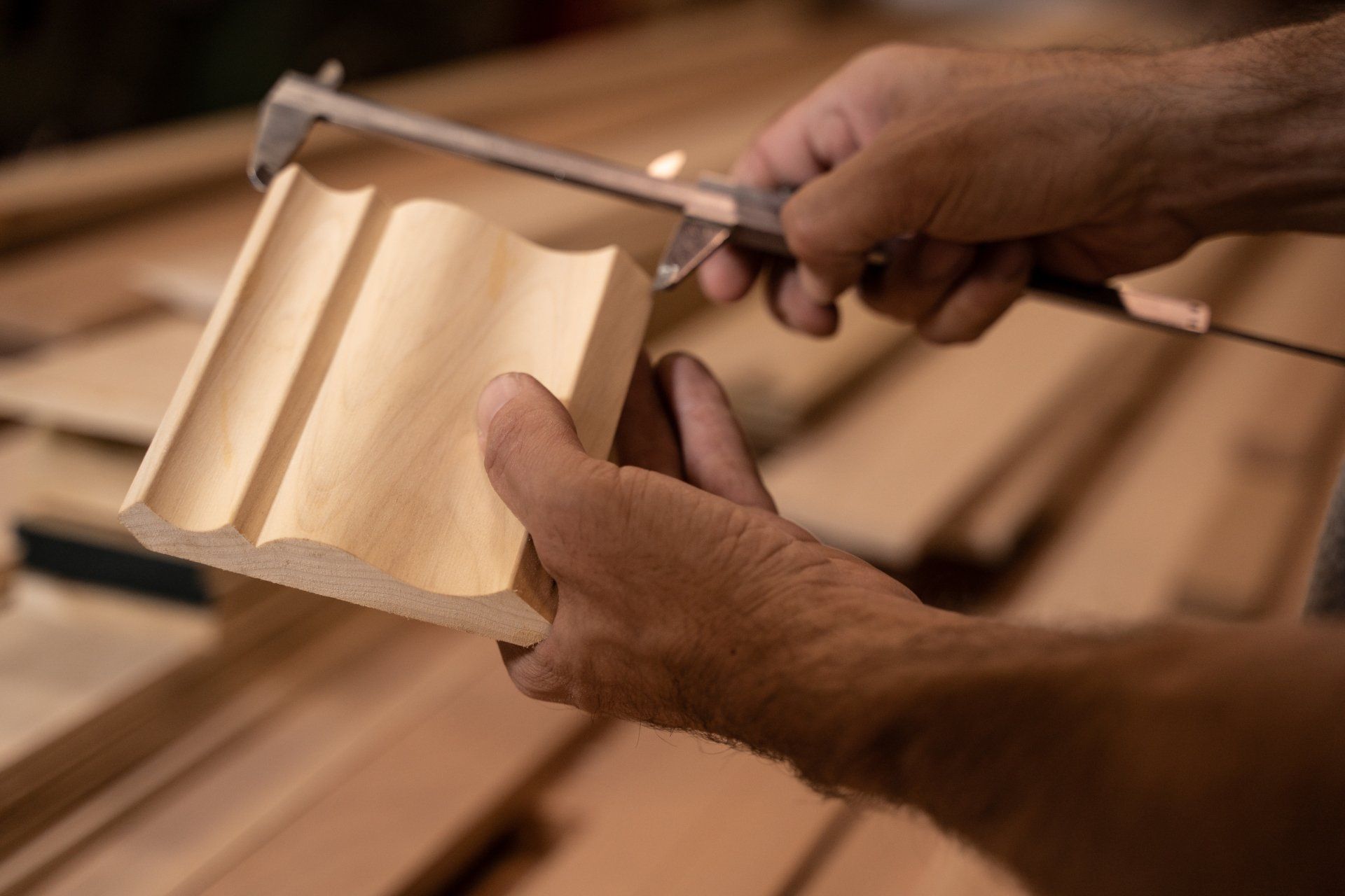 A person is measuring a piece of wood with a caliper.