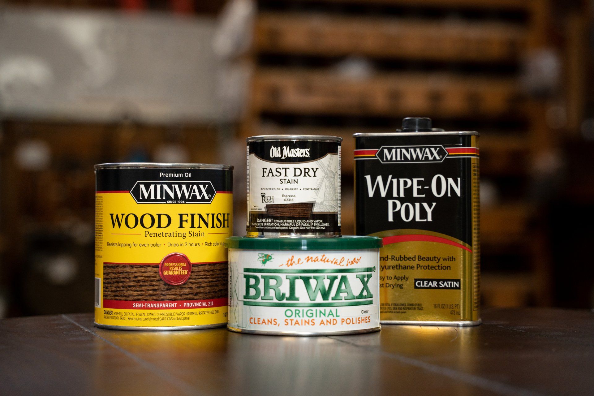 A group of cans of wood finish and wipe on poly are sitting on a table.
