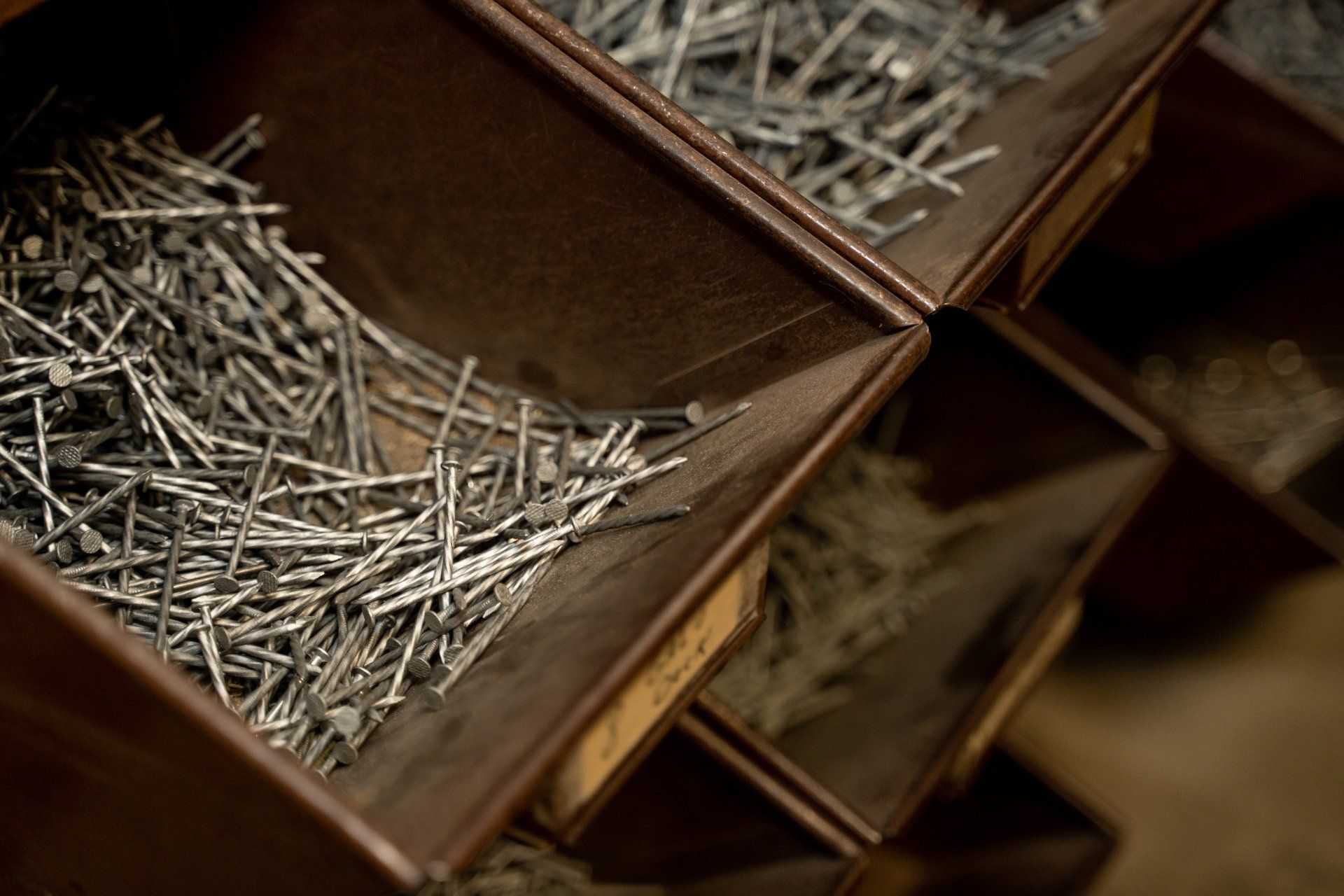 A bunch of nails are in a bin with a label that says ' nails ' on it