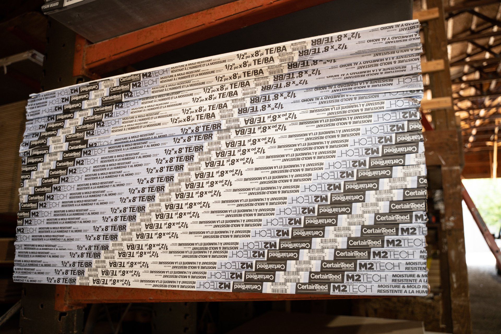 A large stack of drywall is sitting on top of a wooden shelf.