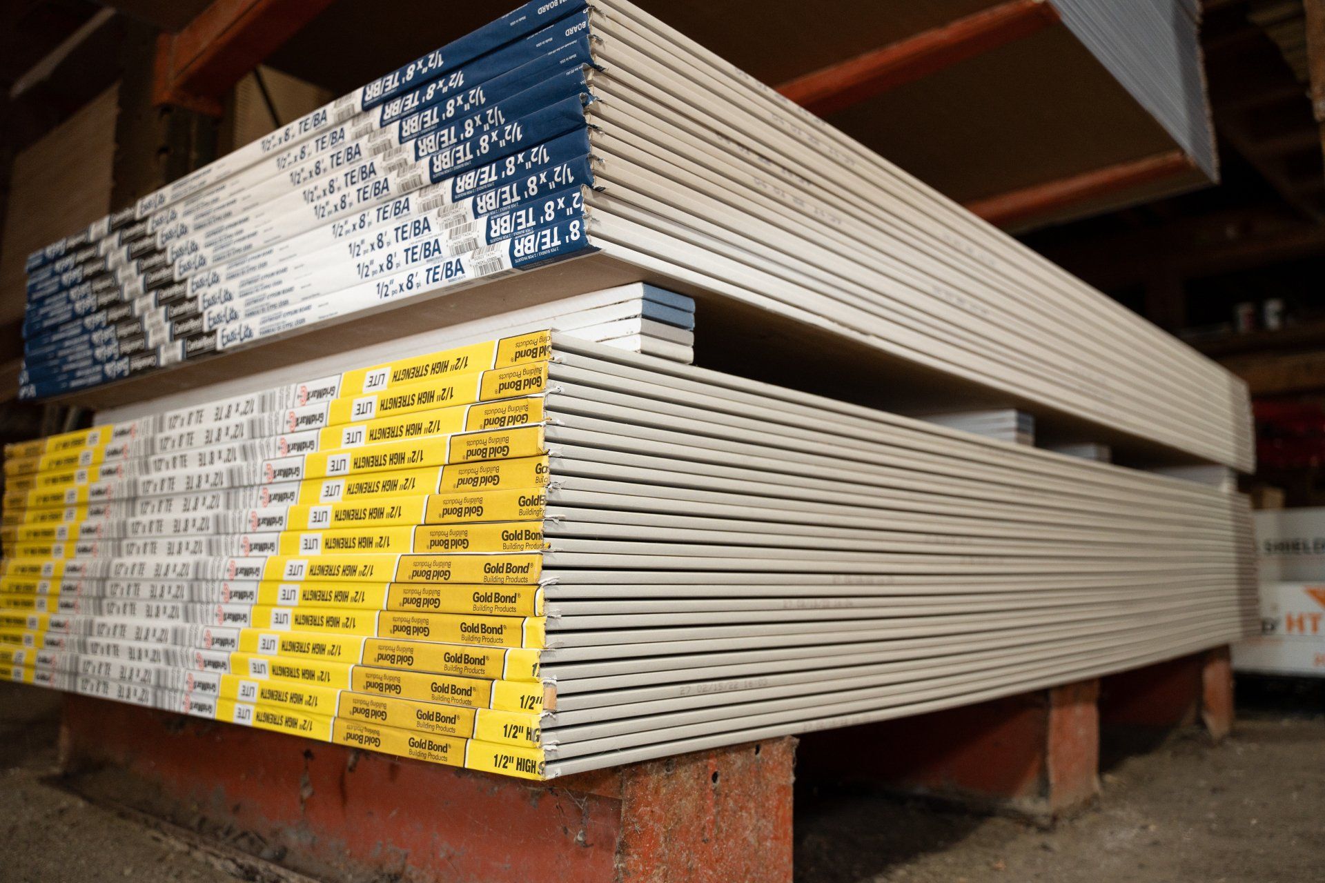 A stack of drywall sheets sitting on top of each other in a warehouse.