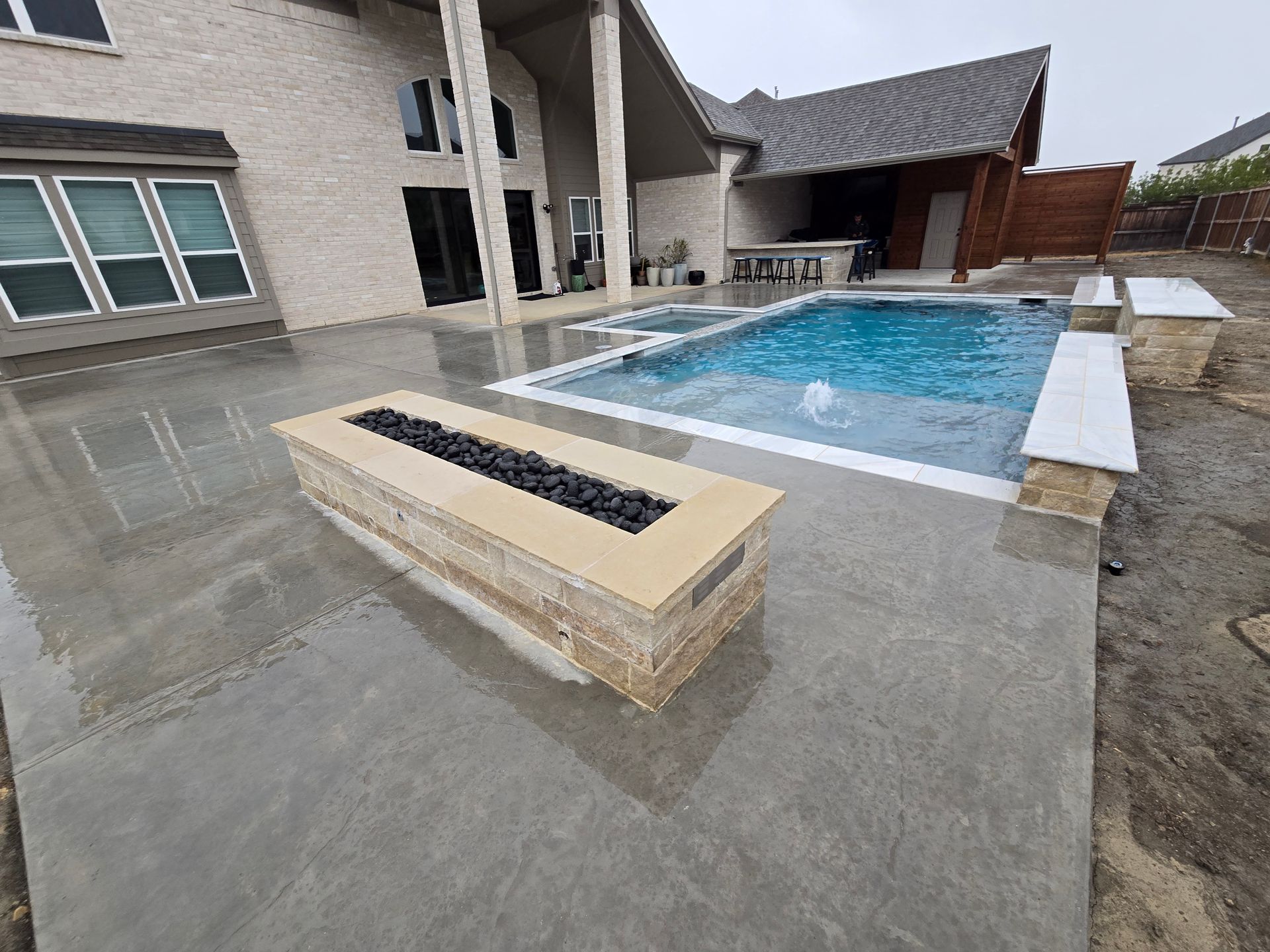 Modern house patio with a rectangular swimming pool and built-in bench seating on a wet concrete deck