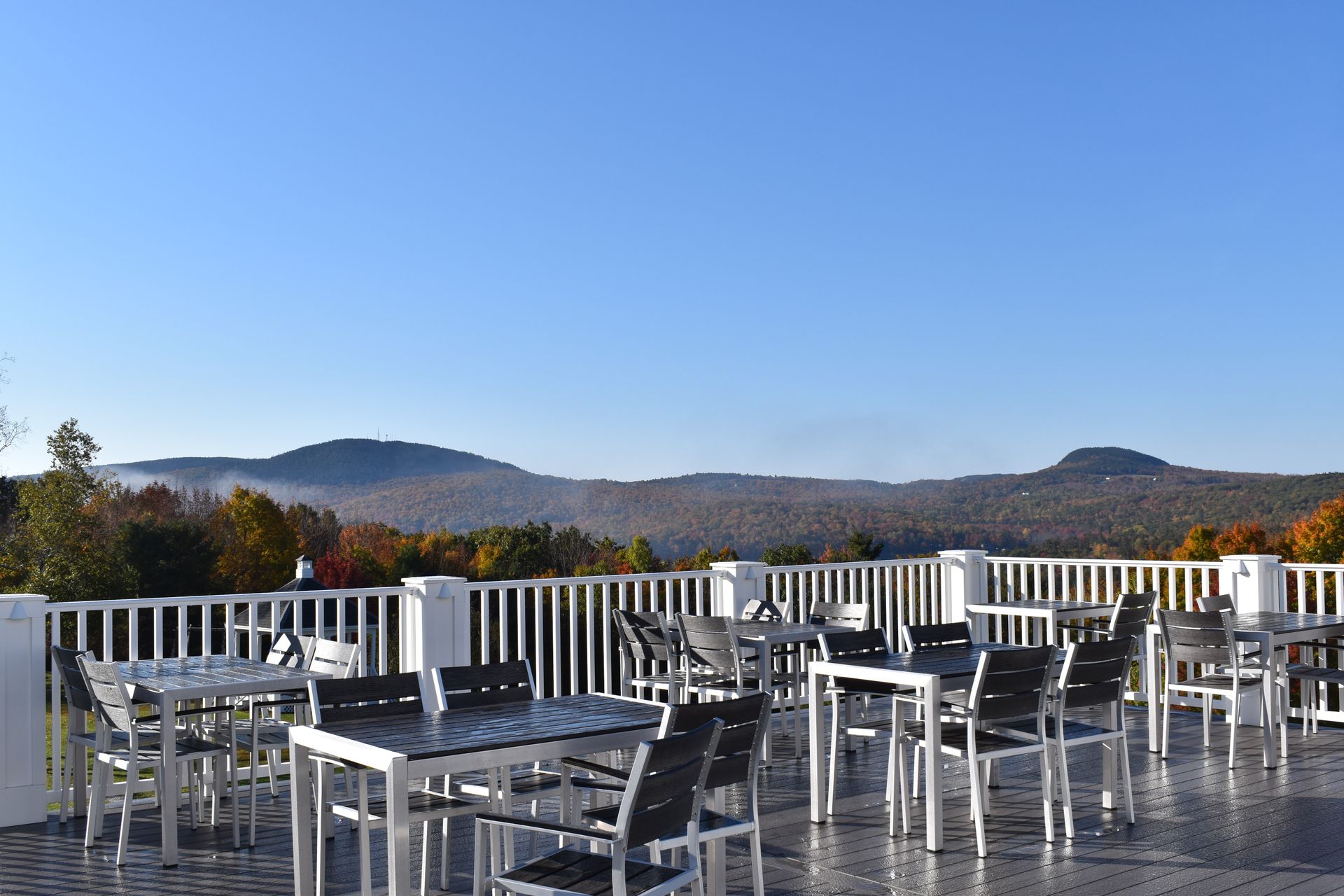 There are many tables and chairs on the patio with a view of the mountains.
