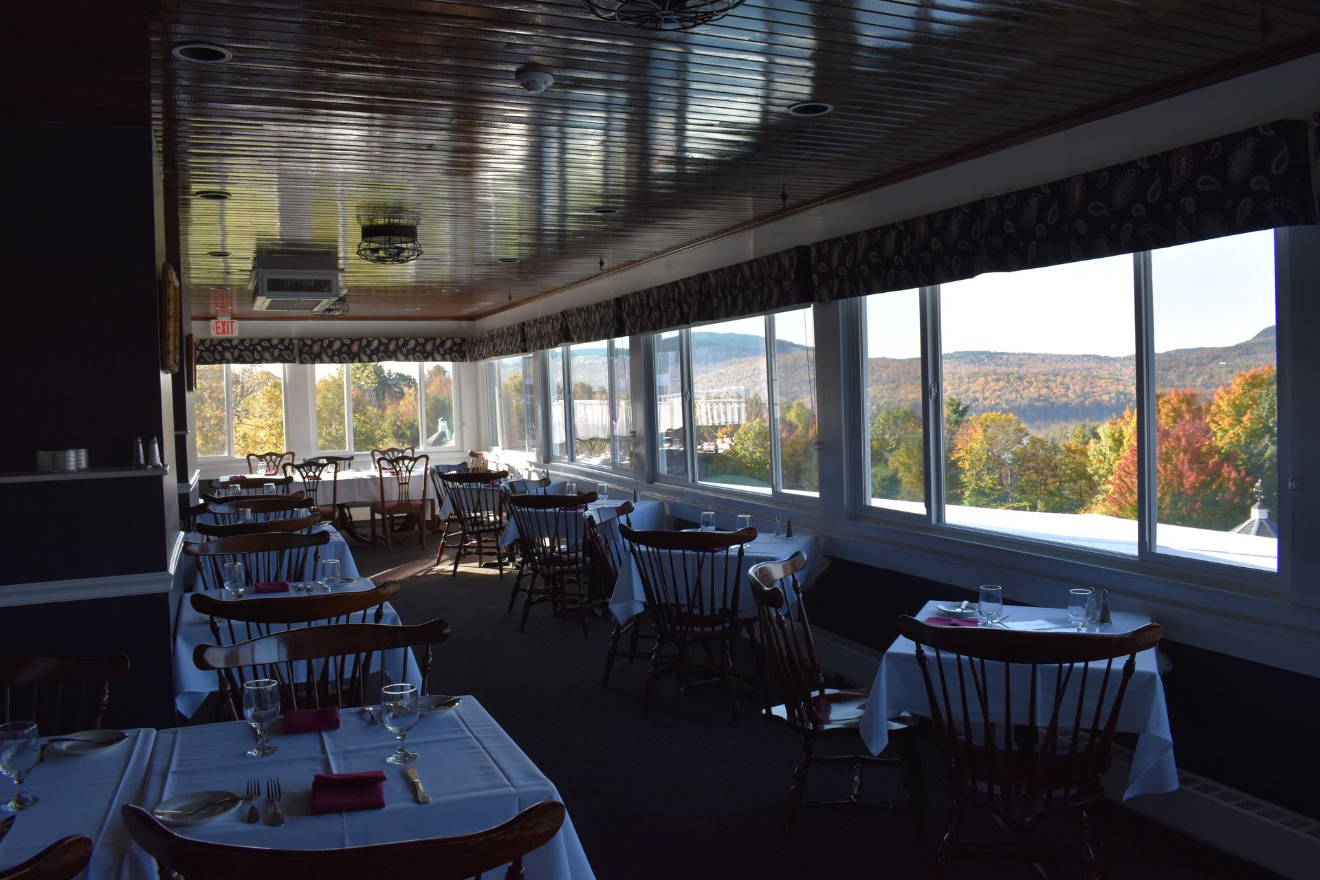 A restaurant with tables and chairs and a view of the mountains.
