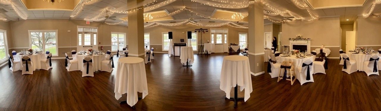 A large room with tables and chairs set up for a wedding reception.