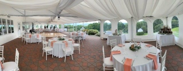 A large tent with tables and chairs set up for a wedding reception.