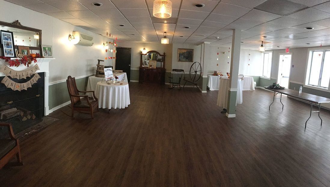 A large room with tables and chairs and a fireplace.