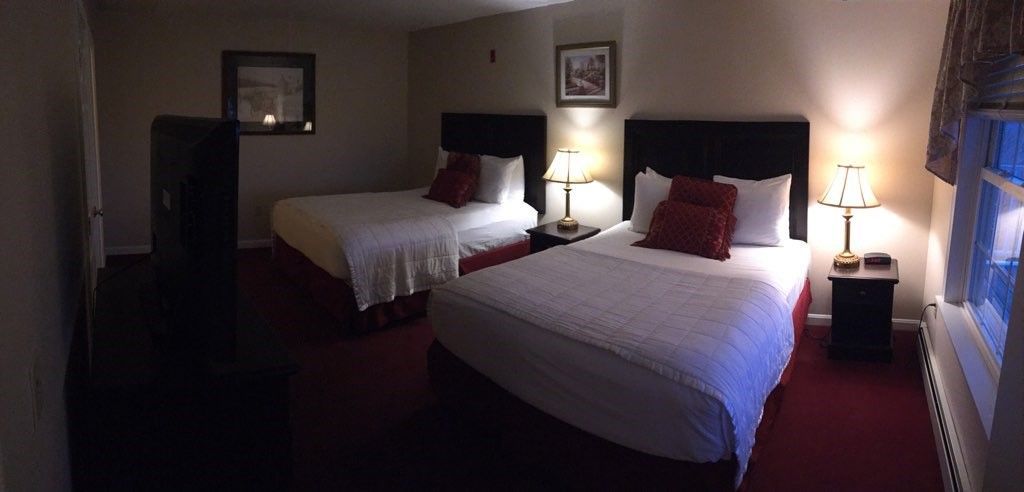 A hotel room with two beds and a television