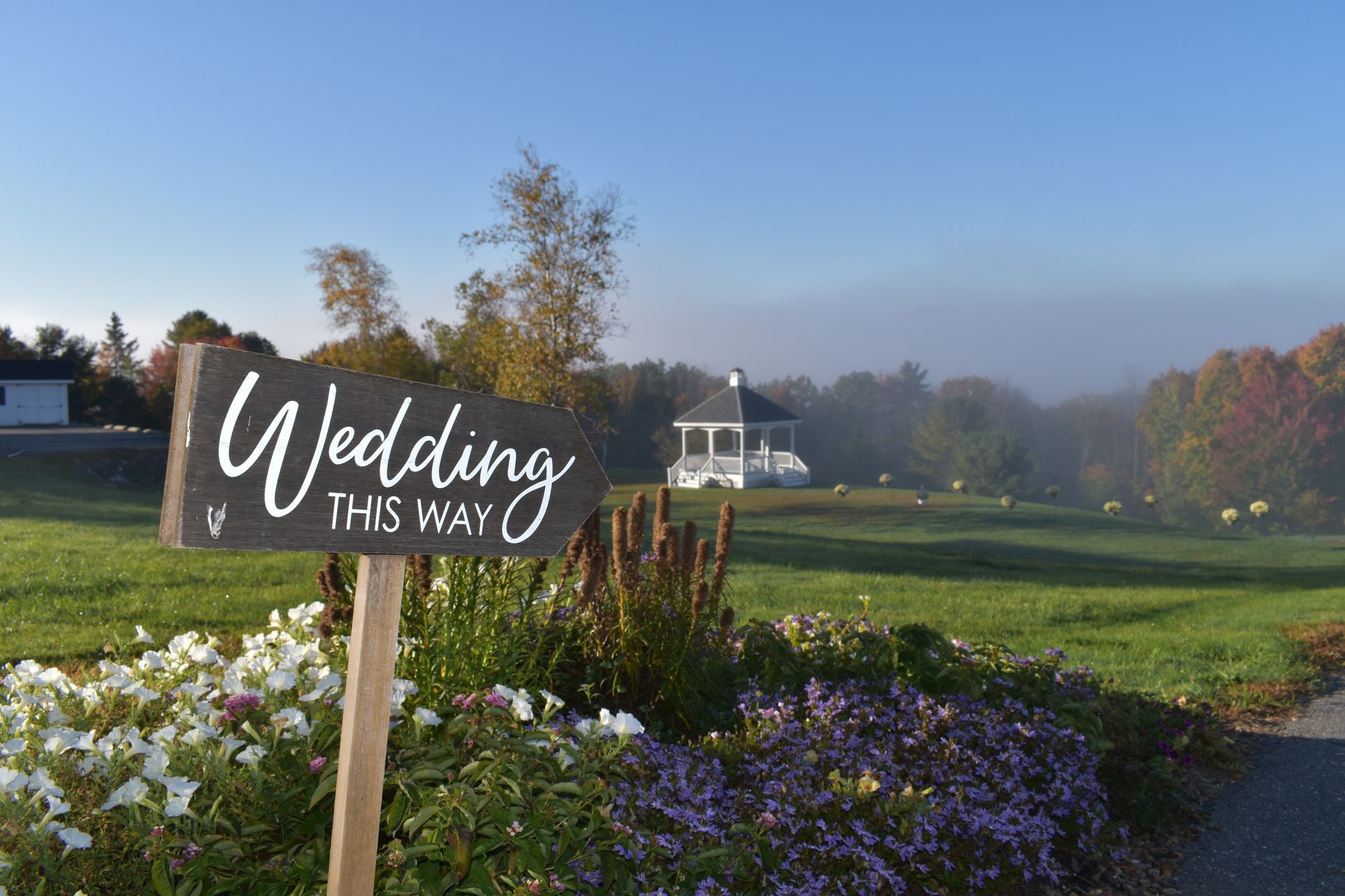 A wedding sign is sitting in the middle of a field.