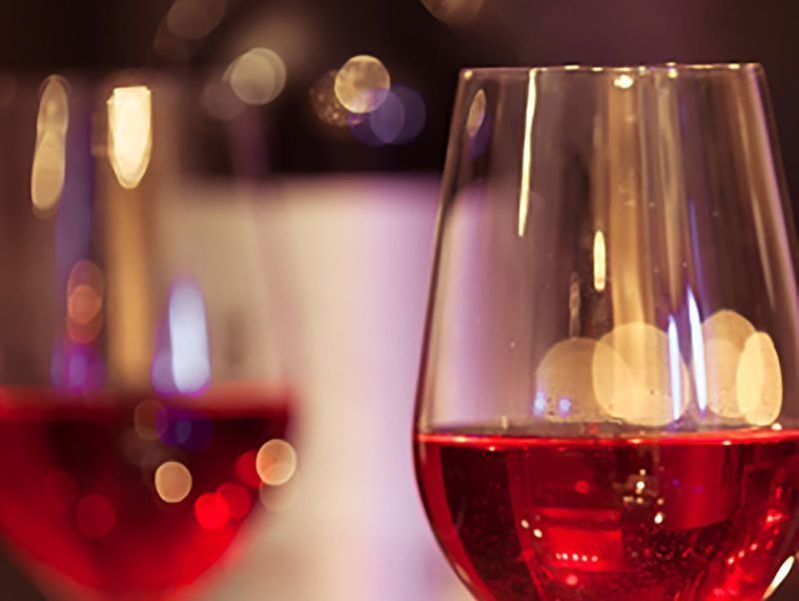 Two glasses of red wine are sitting on a table.