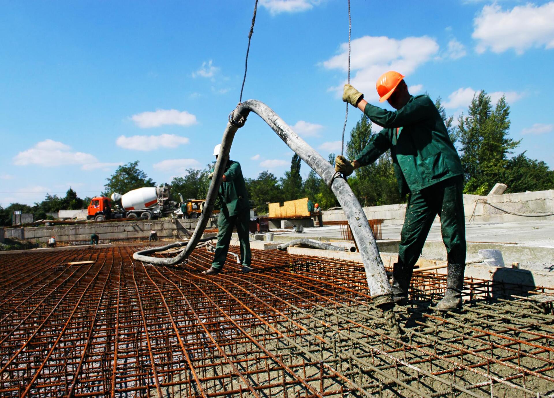 two workers carrying the cement hose