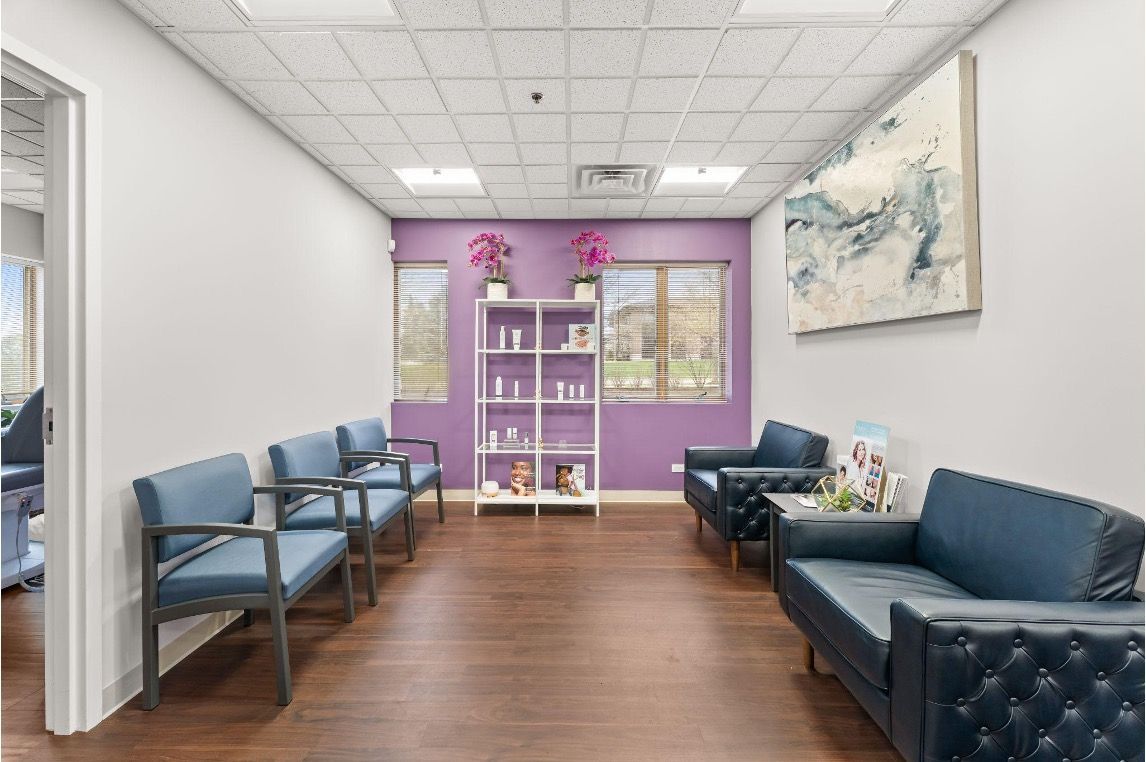 Bright waiting room with blue chairs, purple accent wall, wood floor, and floral wall art