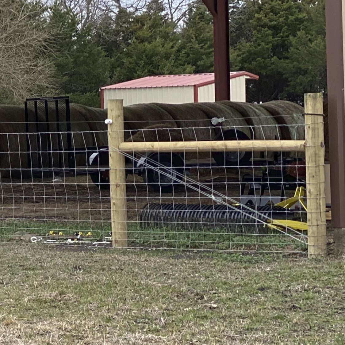 A fence with a bunch of hay bales behind it