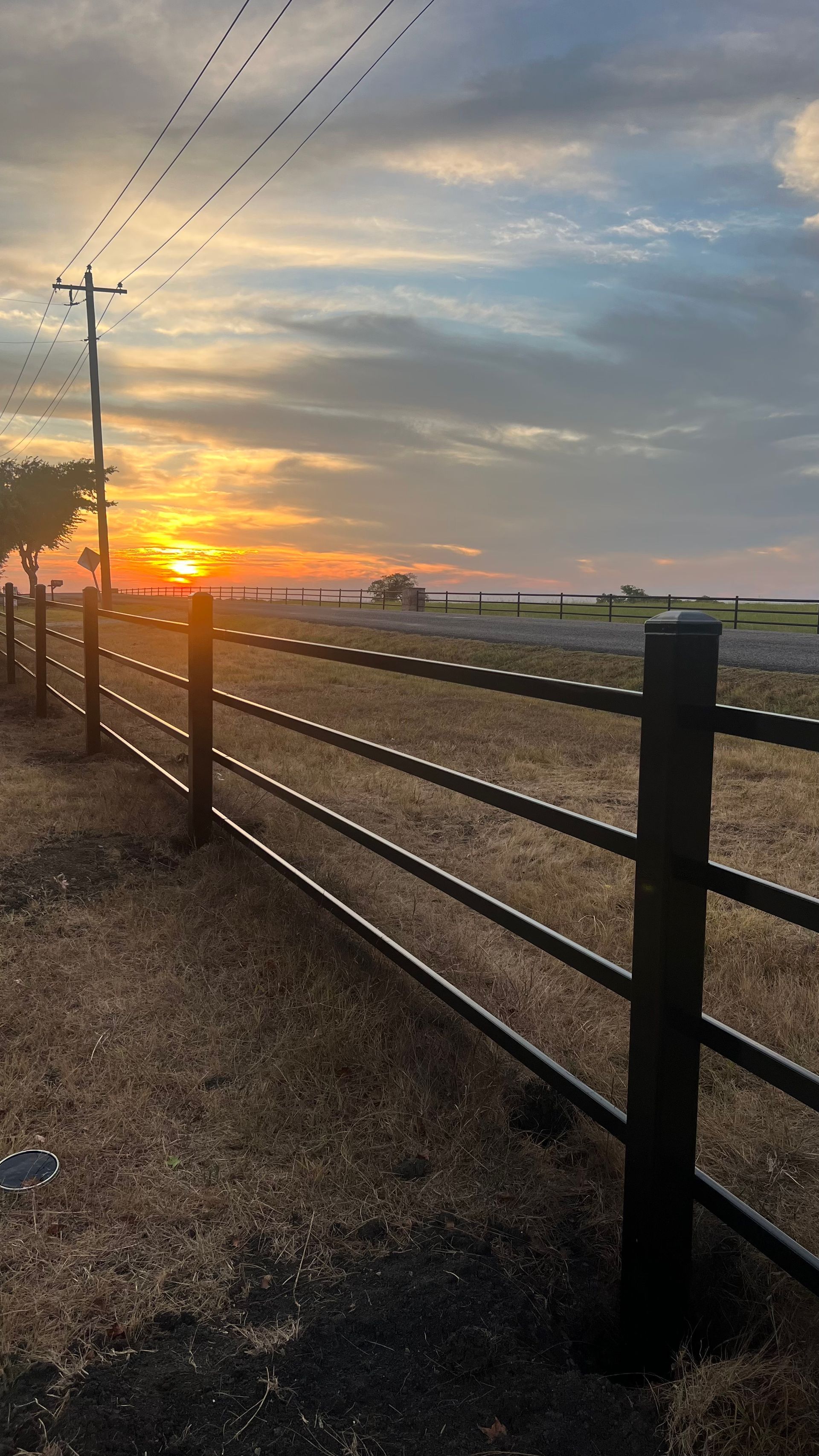 A fence surrounds a field with a sunset in the background.
