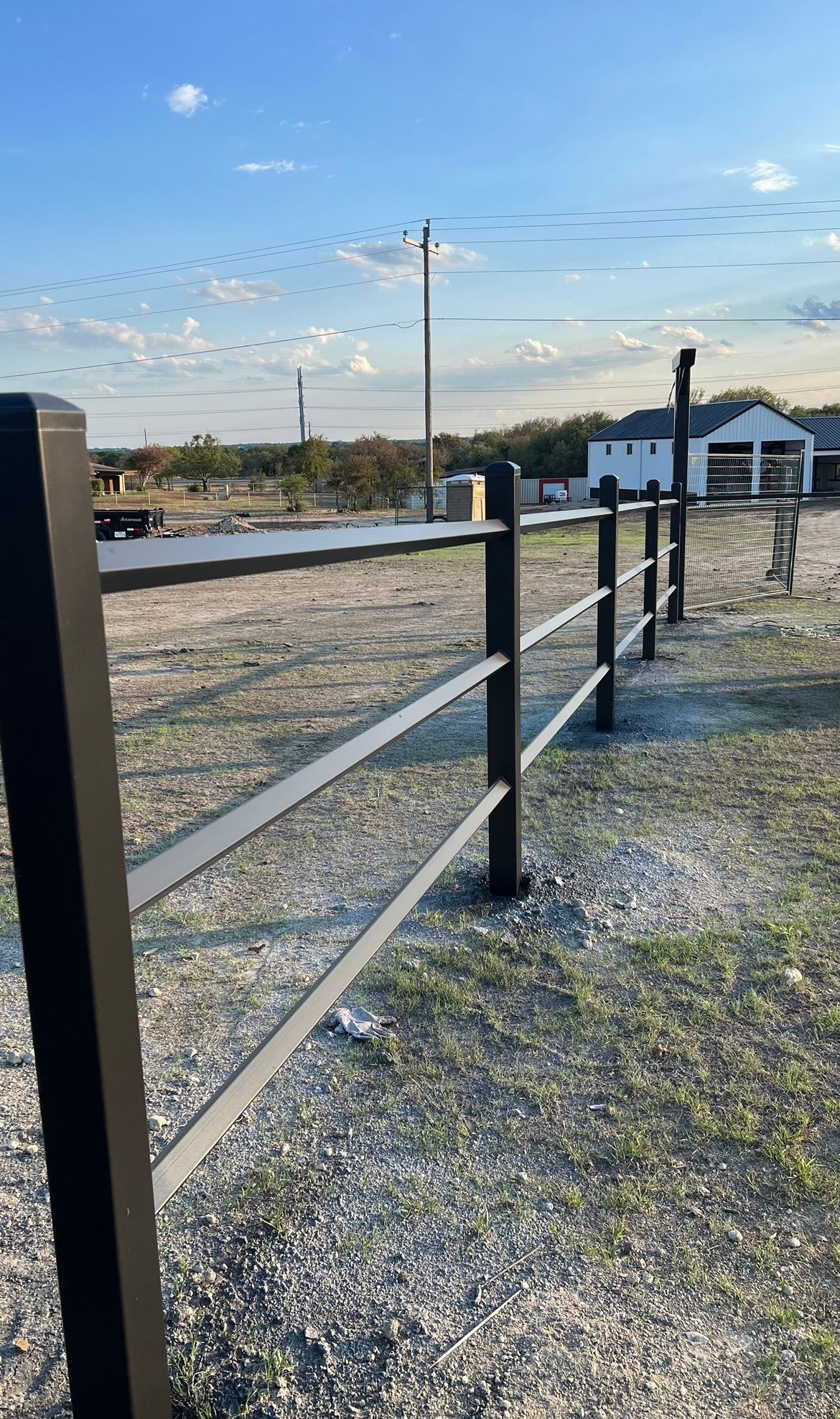 A black fence is sitting in the middle of a dirt field.