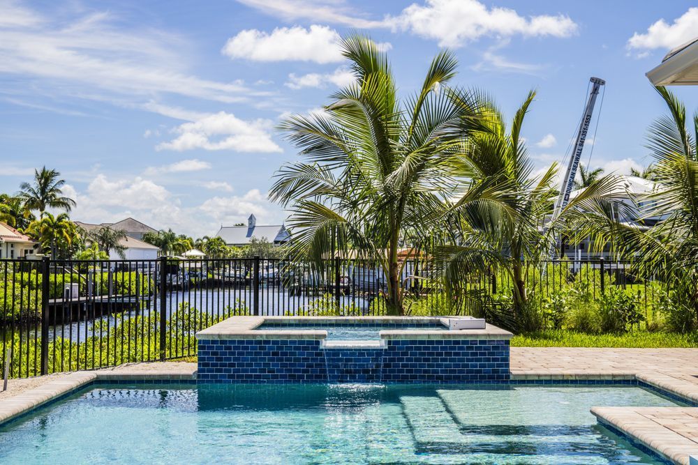 A large swimming pool surrounded by palm trees and a fence.