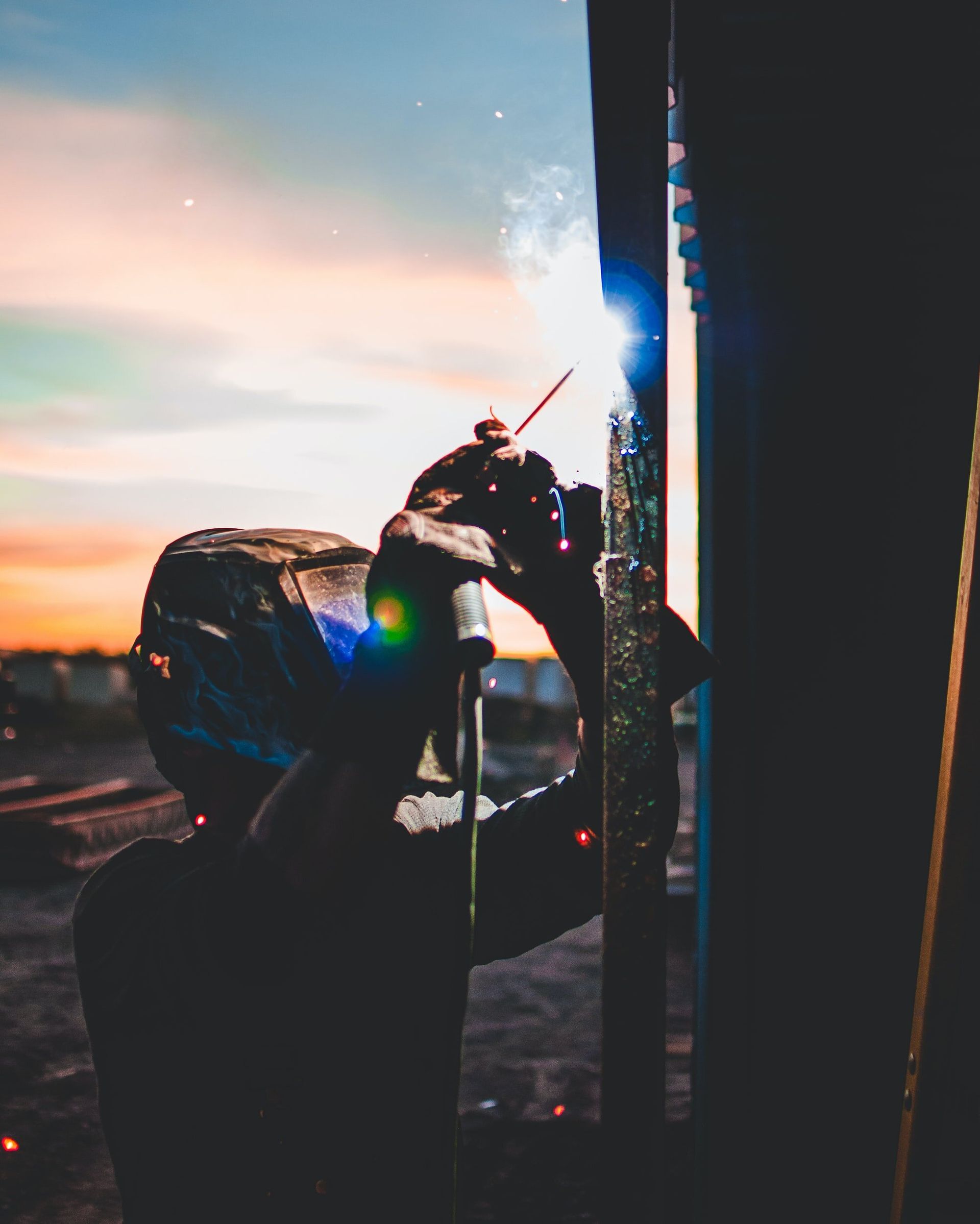 A man wearing a helmet is welding a piece of metal.
