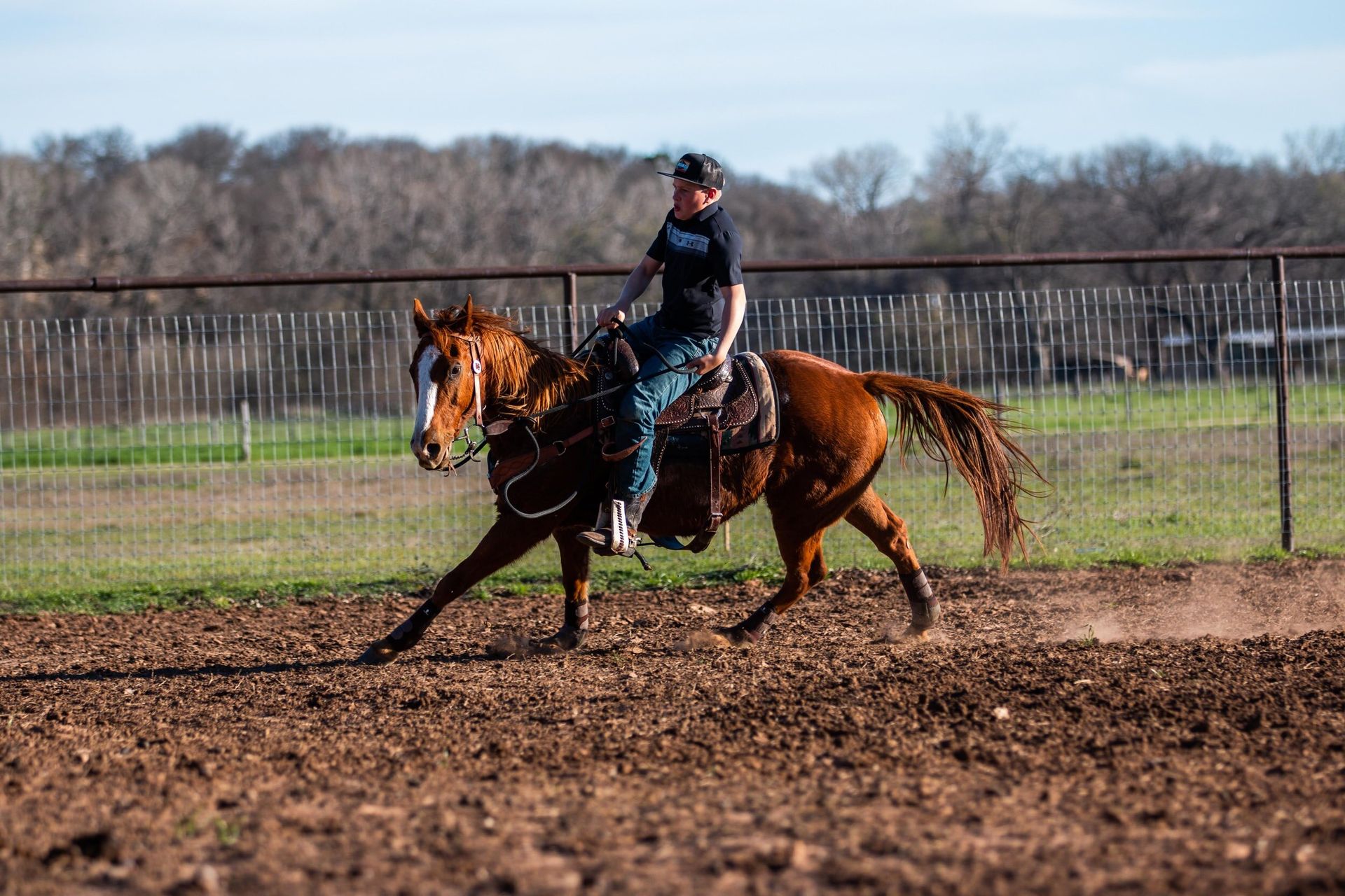 A man is riding a horse in a dirt field.