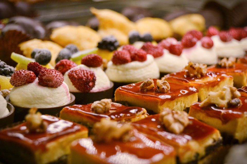 Primo piano di pasticcini assortiti con frutti rossi, panna e noci.