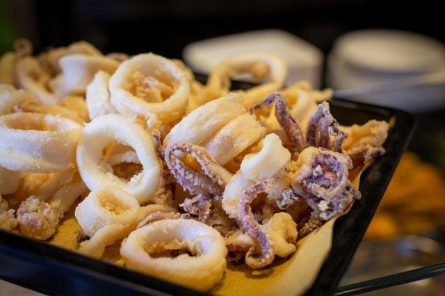 Anelli e tentacoli di calamari fritti in un vassoio nero, primo piano.