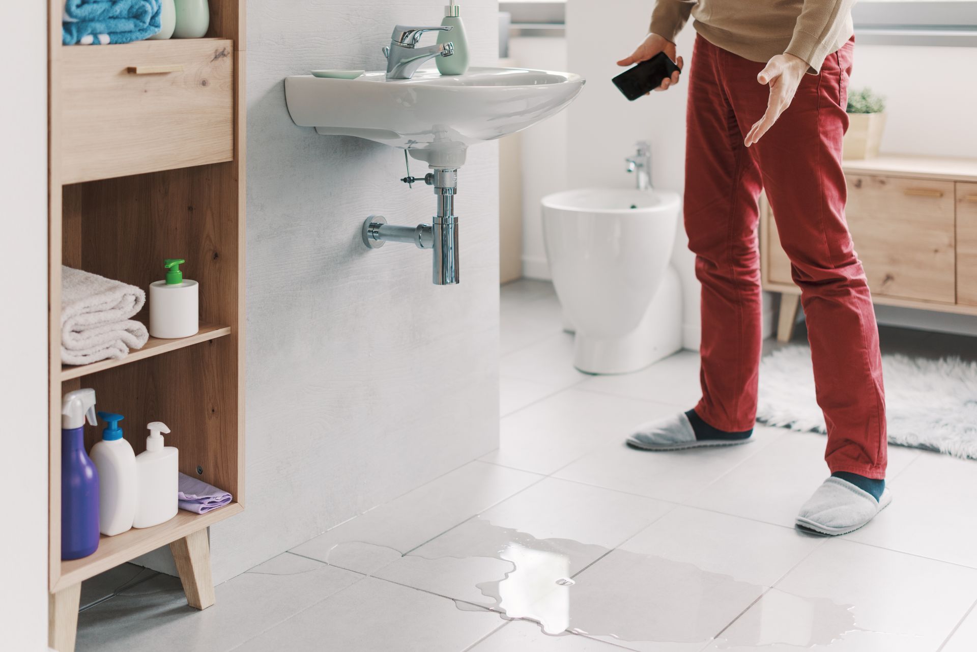 Emergency plumbing services responding to a bathroom water leak with standing water on the tile floor near a sink and toilet. Emergency plumbing services responding to a bathroom water leak with standing water on the tile floor near a sink and toilet.