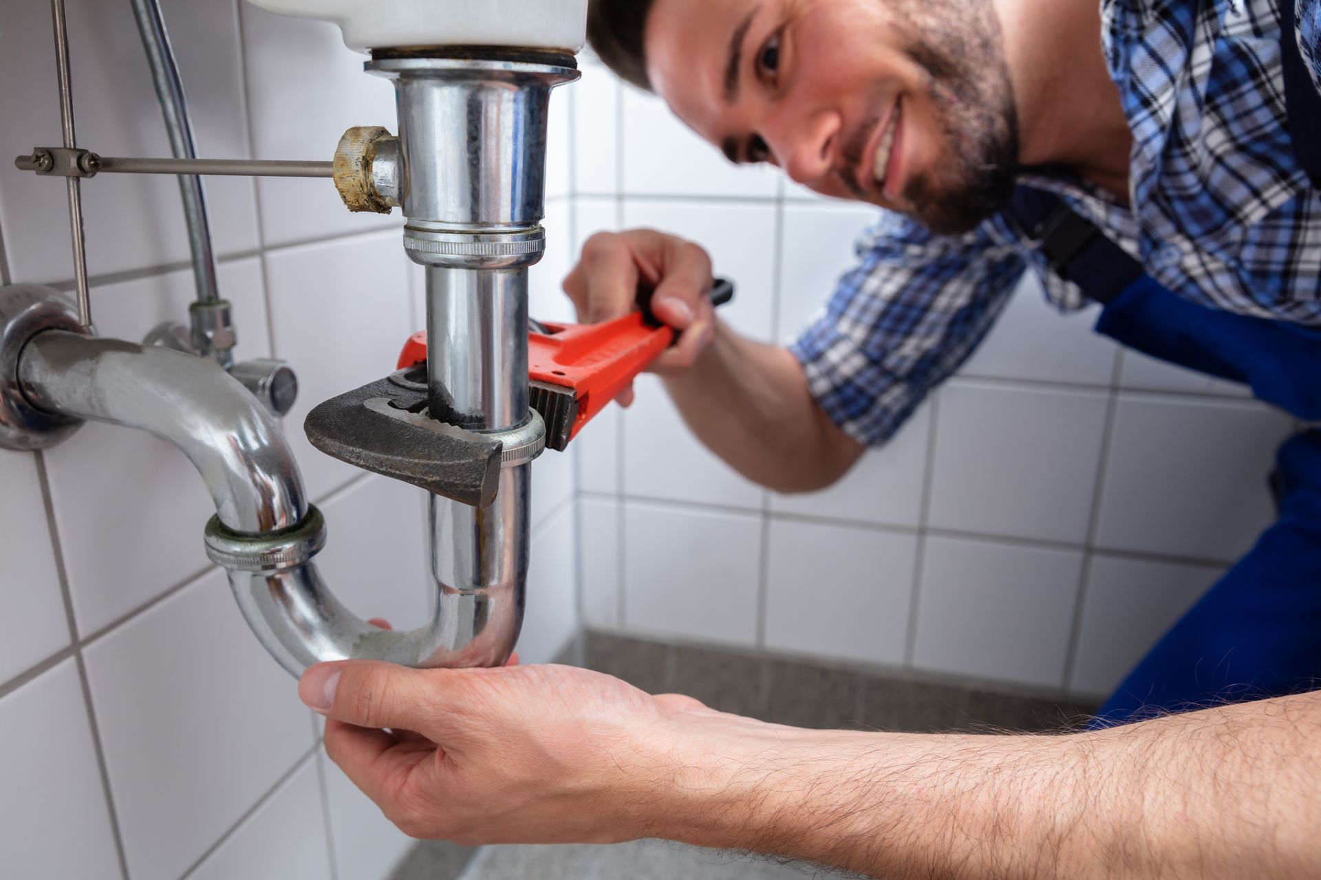 Plumber Repairing Sink In Bathroom