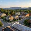 Aerial view of a quiet neighborhood with houses, streets, trees, and mountains at sunset