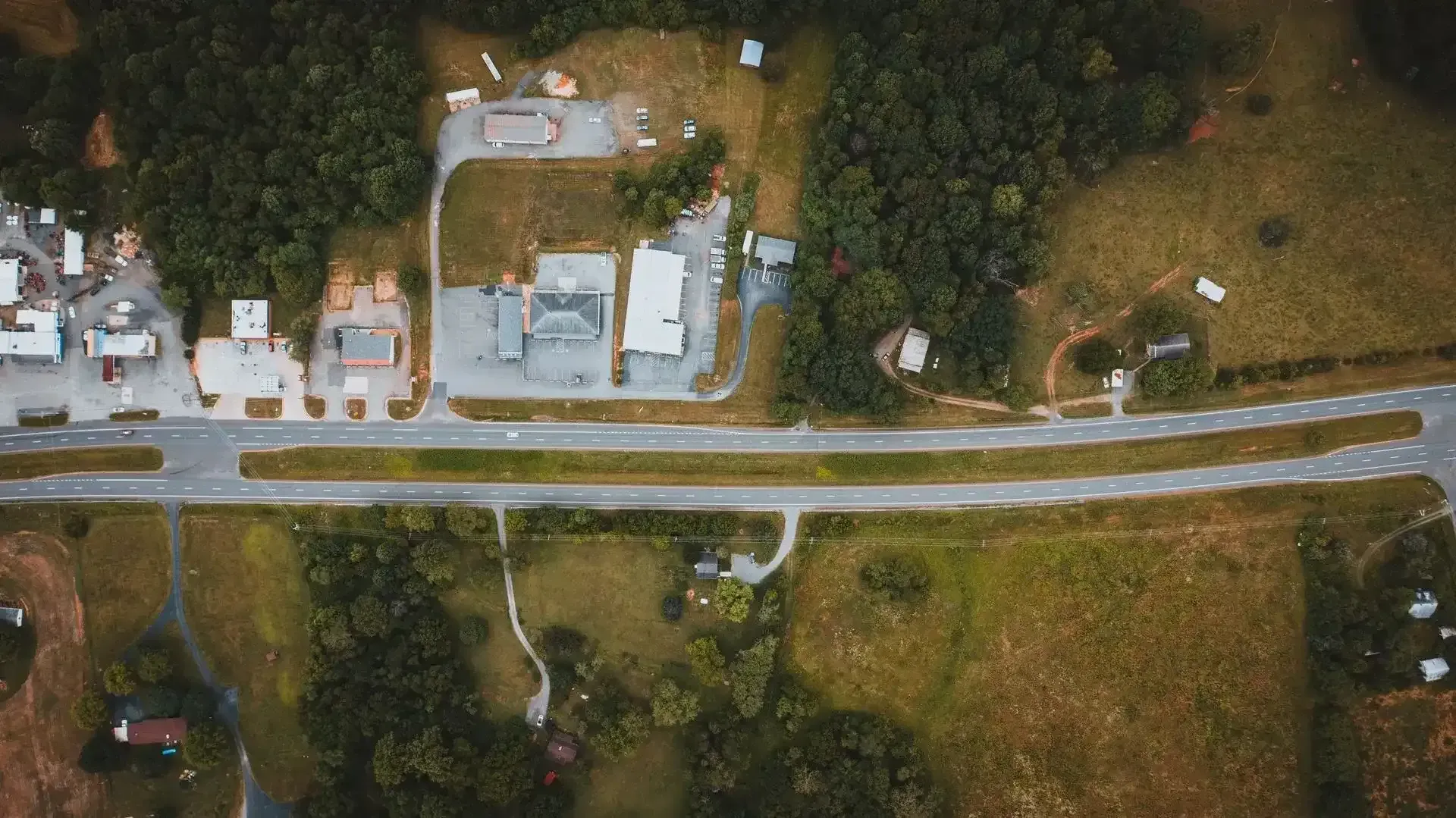 Aerial view of a quiet neighborhood with houses, streets, trees, and mountains at sunset