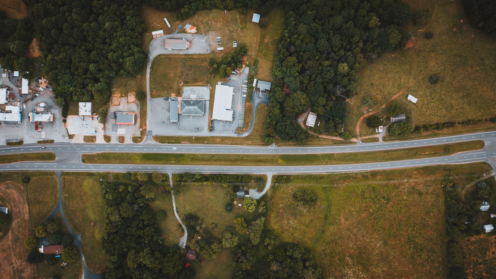 Aerial view of a quiet neighborhood with houses, streets, trees, and mountains at sunset