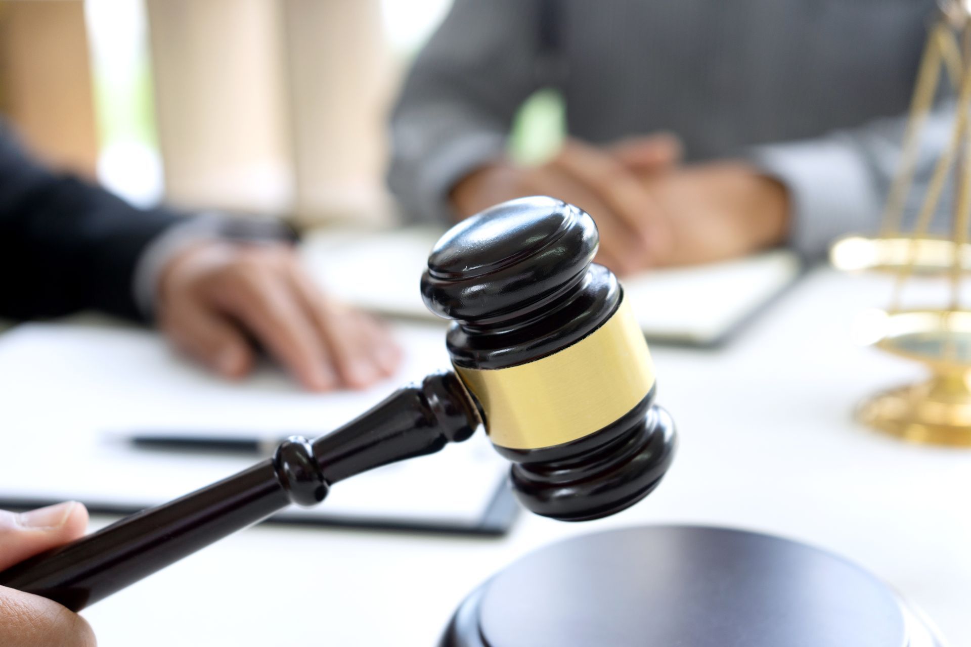 Gavel in hand, legal proceeding with figures in background.