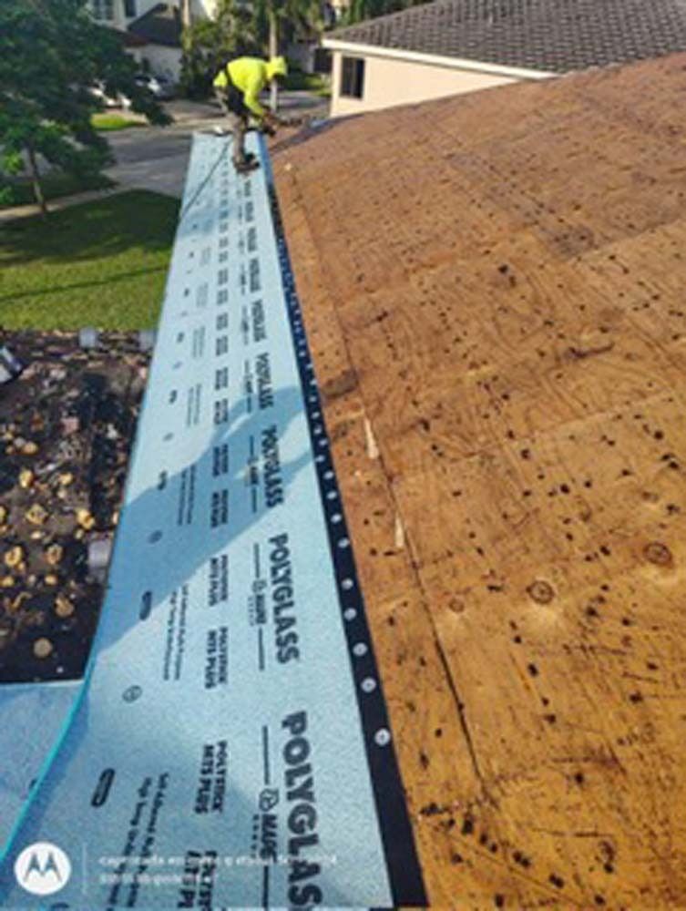 A worker in a yellow high-visibility shirt installs Polyglass roofing underlayment on a plywood roof deck.
