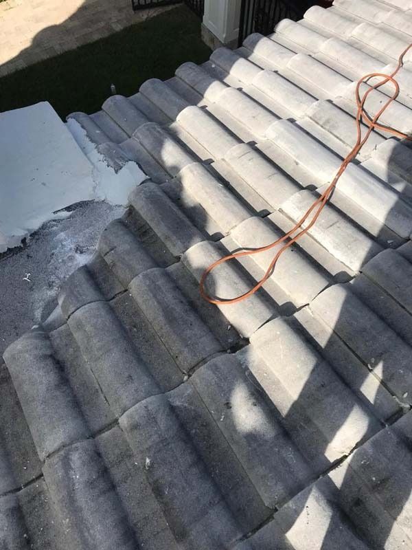 A view from above looking down a gray tiled roof with a coiled orange safety rope resting on the surface.