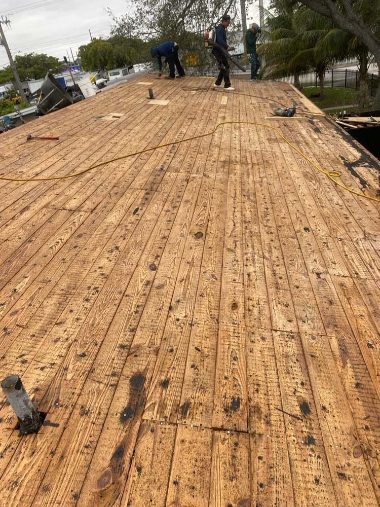 Workers on a wooden rooftop during construction, with a residential neighborhood visible in the background.